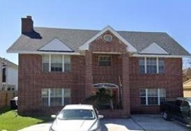 A brick house with a white car parked in front.