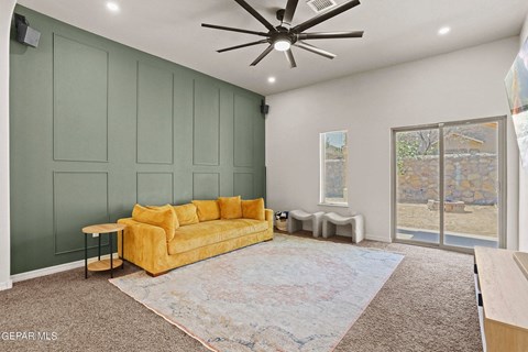 A living room with a yellow couch and a ceiling fan.