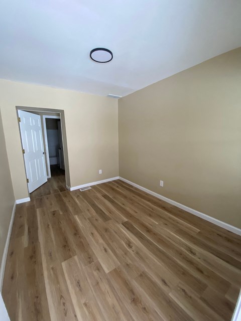 A room with wooden flooring and a white door.