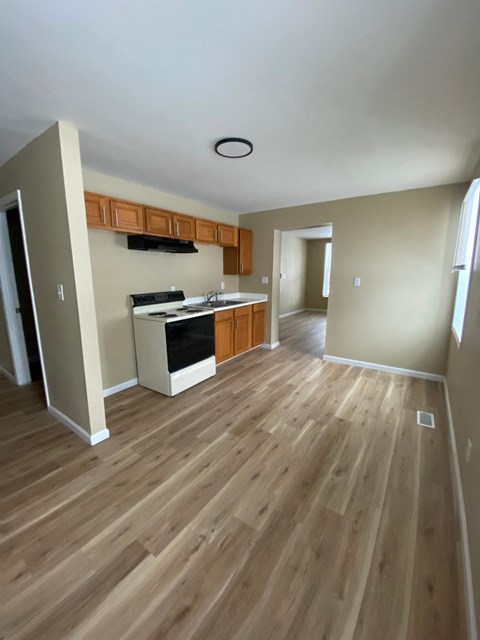 A kitchen with wood flooring and a ceiling fan.