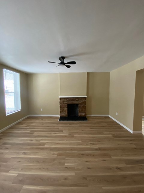 A room with a fireplace and a ceiling fan.