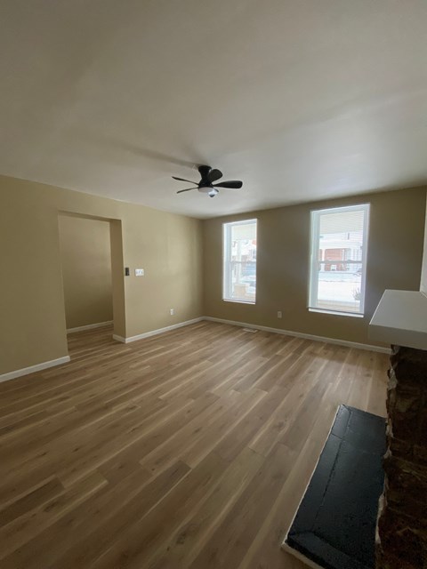 A room with a ceiling fan and wooden flooring.