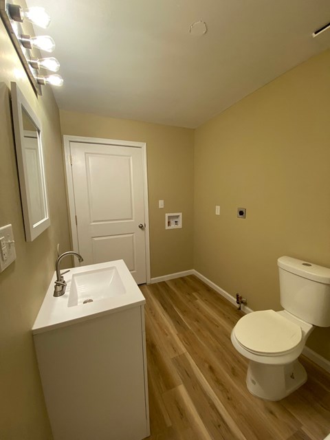 A bathroom with a toilet, sink, and mirror.