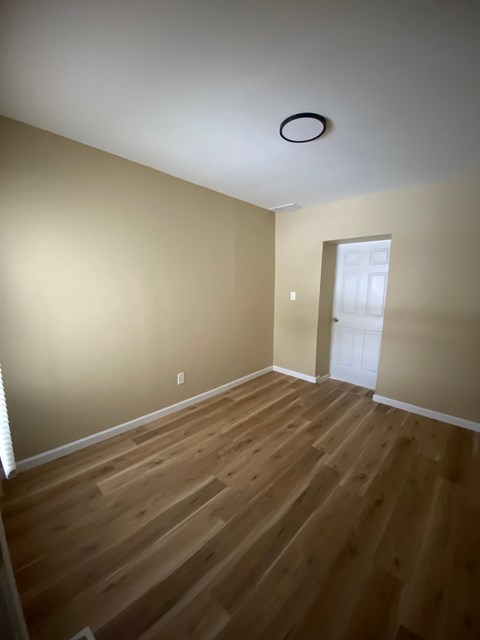 A room with wooden flooring and a white door.
