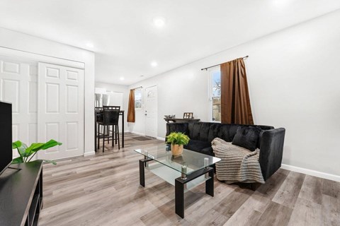 A black couch with a striped pillow sits in a living room with a glass coffee table.