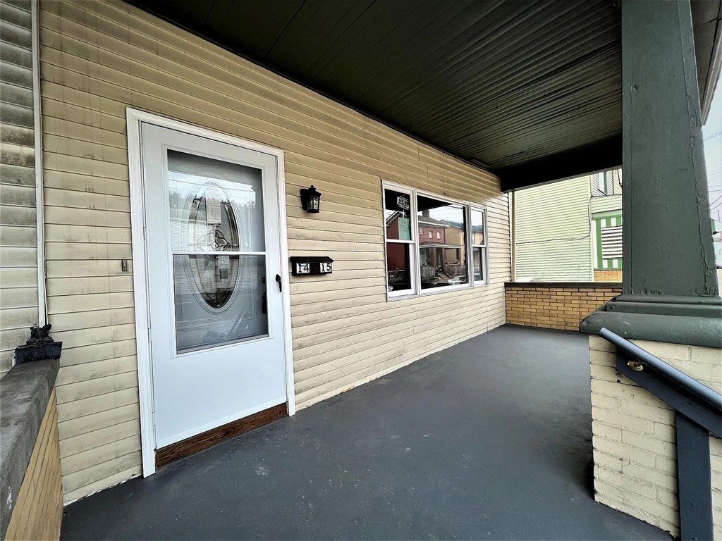 A white door is on the left side of a building with a porch.