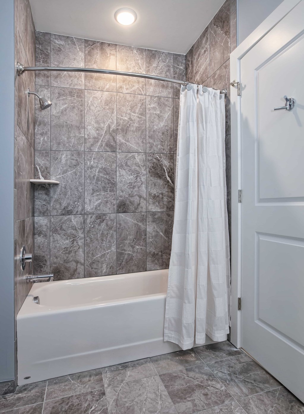 A white bathtub with a shower head and a white shower curtain.