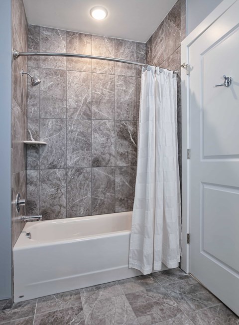 A white bathtub with a shower head and a white shower curtain.