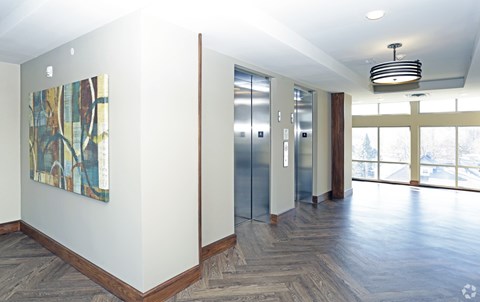 A hallway with wood floors, a ceiling light, and a painting on the wall.