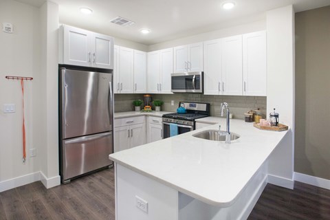 A kitchen with white cabinets and a stainless steel refrigerator.