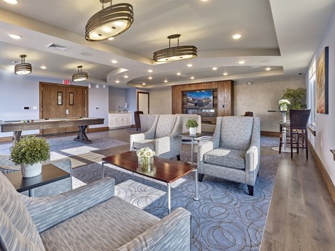 A spacious living room with grey furniture and a pool table.