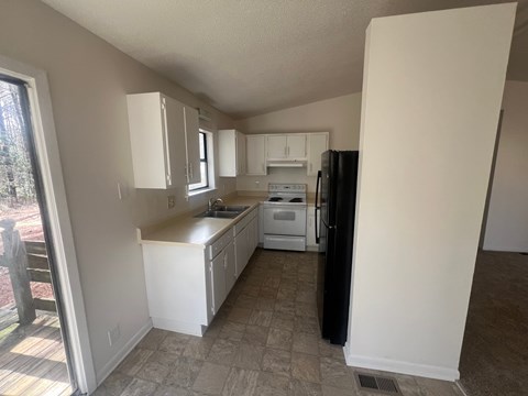 A kitchen with white cabinets and a black refrigerator.