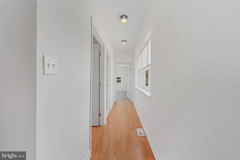 A long hallway with a light on the ceiling and a door at the end.
