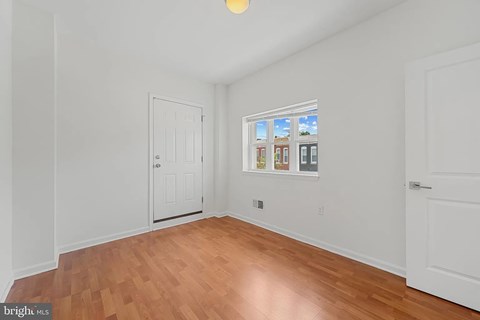 A room with a white door and a window showing a view of buildings.