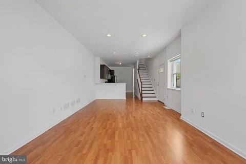 A spacious room with wooden floors and a staircase.