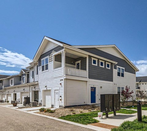 A modern two-story house with a balcony and a blue door.