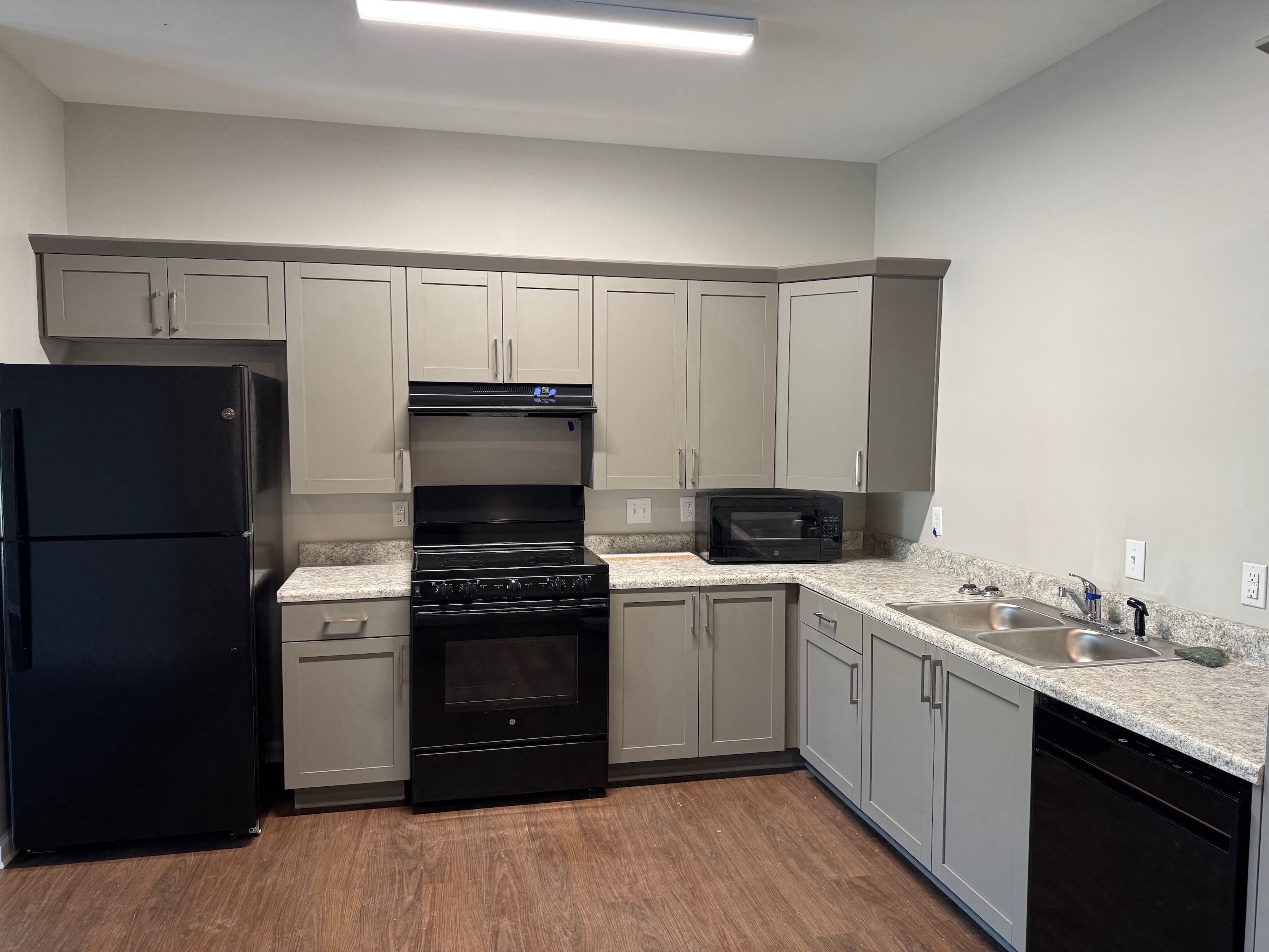 A kitchen with black appliances and wooden floors.