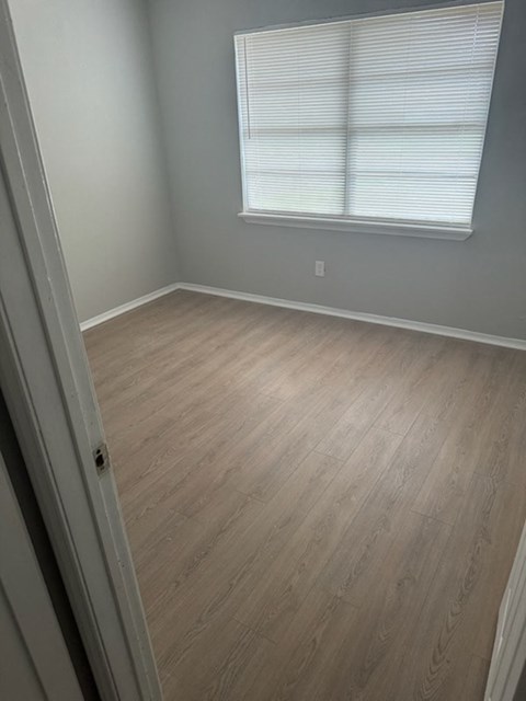 A room with a light grey wall and a window with blinds.