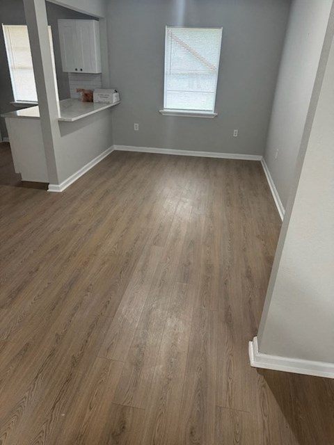 A room with wooden flooring and a window with blinds.