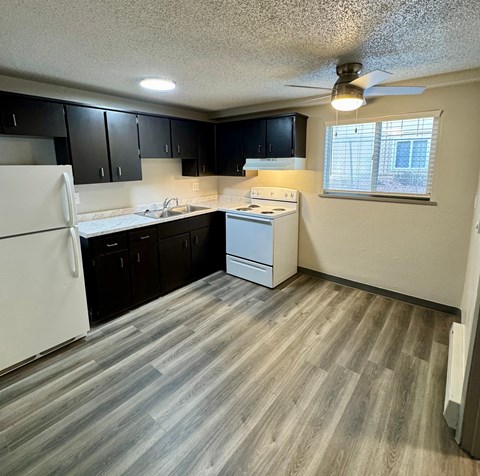 A kitchen with white appliances and black cabinets.