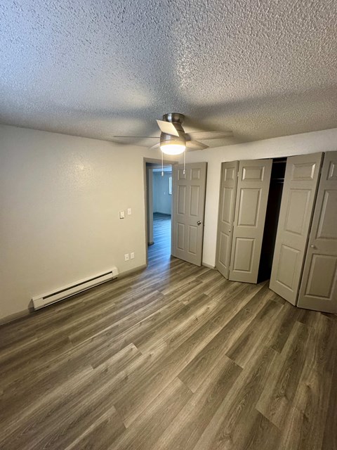 A room with wooden flooring and a ceiling fan.