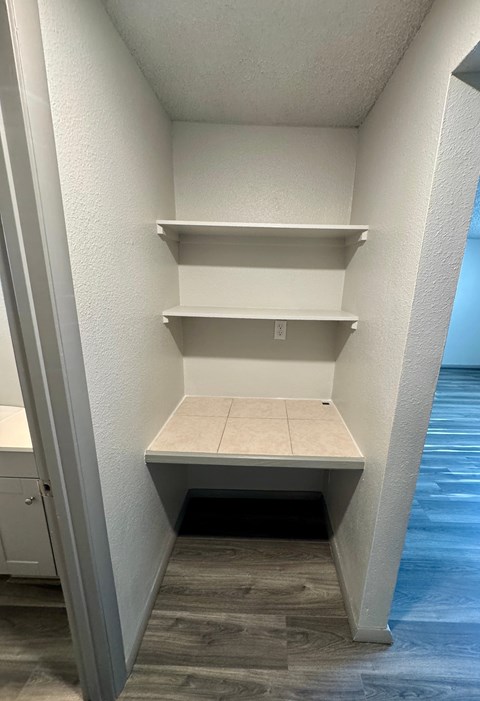 A white pantry with a door open to a hallway.