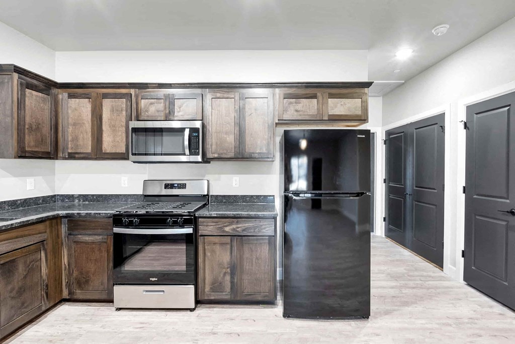A kitchen with a black refrigerator and wooden cabinets.