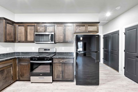 A kitchen with a black refrigerator and wooden cabinets.