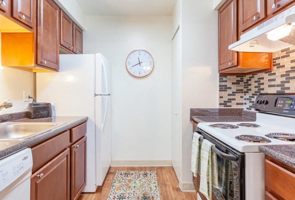 A kitchen with a white fridge, white stove, and brown cabinets.