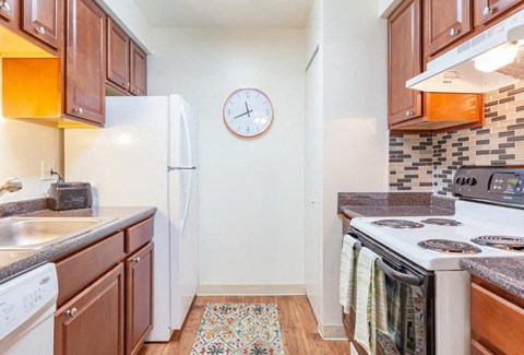 A kitchen with a white fridge, white stove, and brown cabinets.