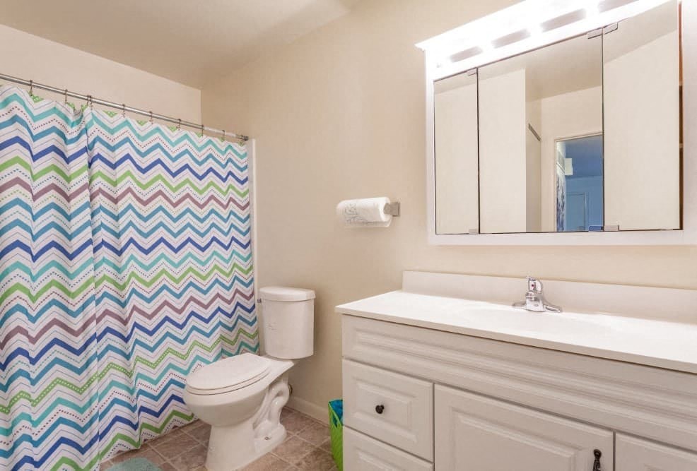 A bathroom with a white toilet, a white sink, and a colorful shower curtain.