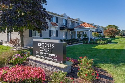 A sign for Regents Court Apartment Homes is in front of a building.
