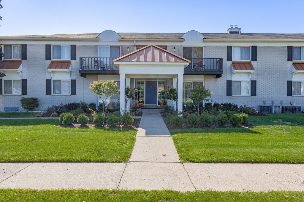 A building with a balcony and a small tree in front of it.