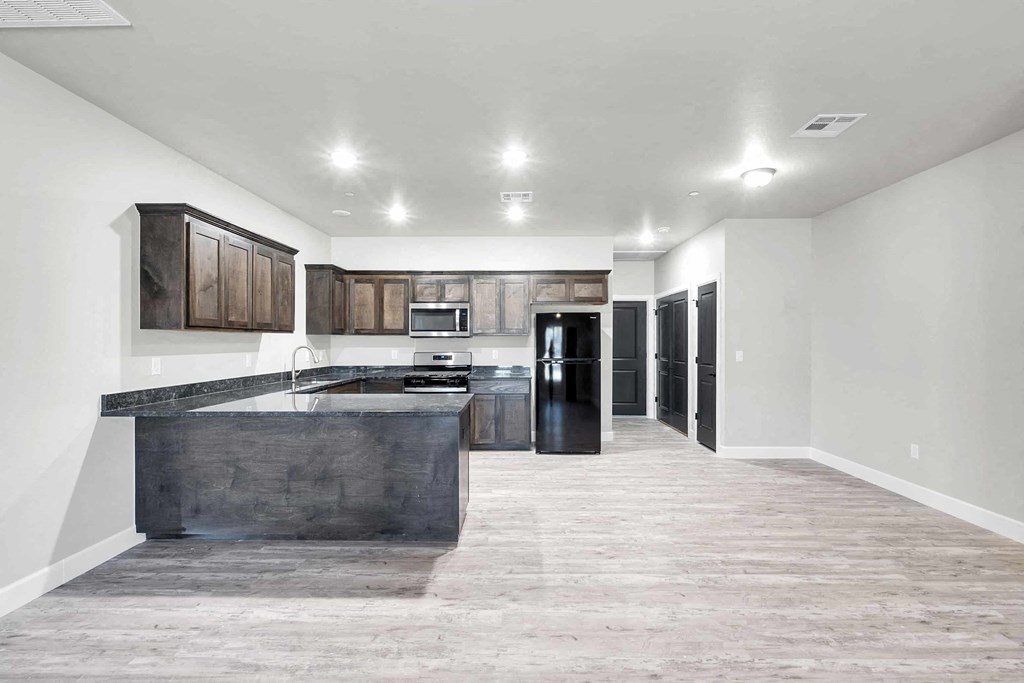 A kitchen with a dark counter top and wooden cabinets.