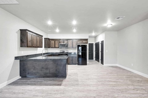 A kitchen with a dark counter top and wooden cabinets.