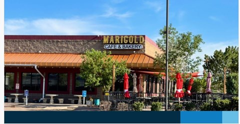 The Marigold Cafe & Bakery has a red awning and red umbrellas outside.