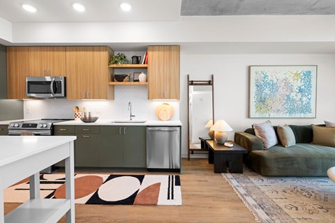 A modern kitchen with a greenish tone to the cabinets and a white dining table.