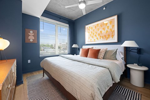 A bedroom with a bed, nightstand, and a painting on the wall.