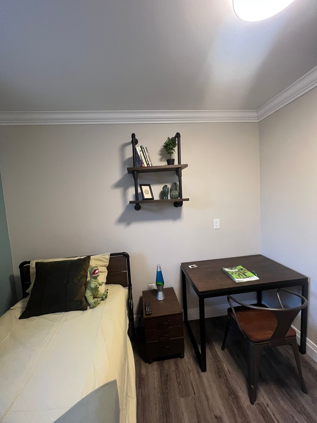 A bedroom with a bed, nightstand, and a table with a chair.