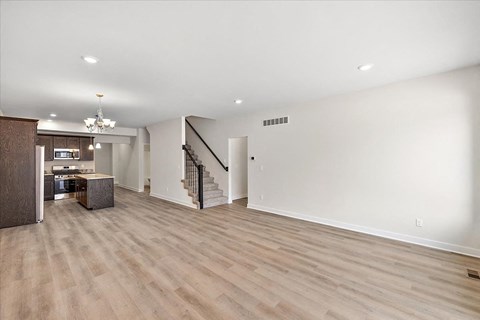 A spacious room with wooden flooring and a staircase.