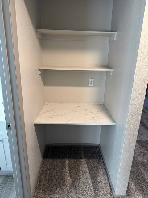 A white pantry with a marble countertop and a striped carpet.