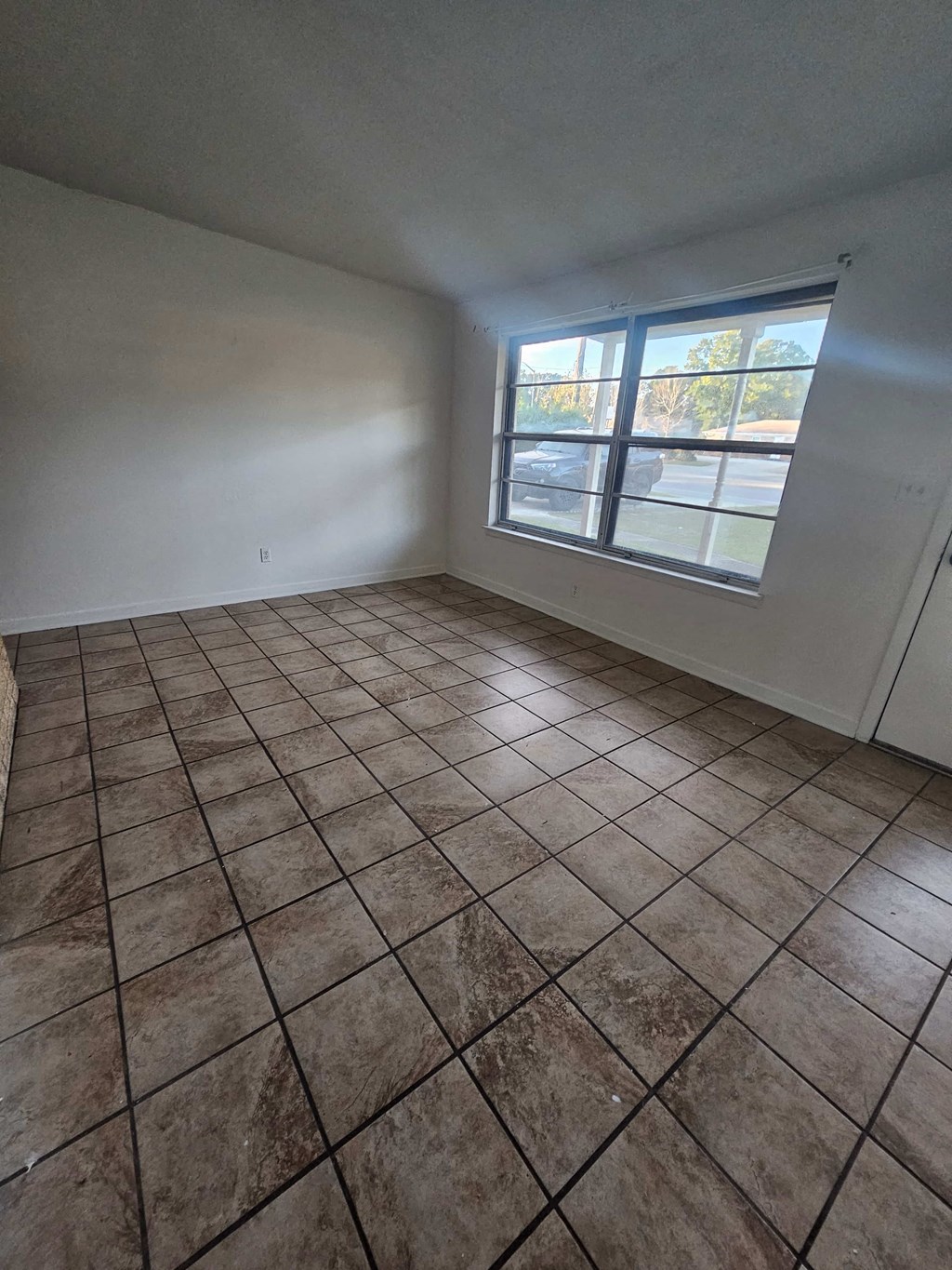 A room with a large tiled floor and a window.