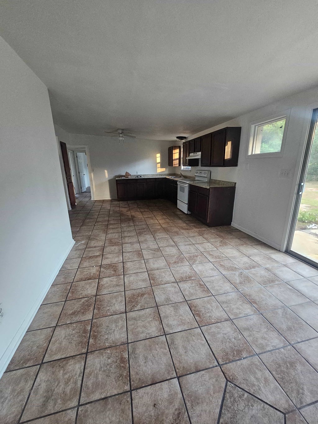 A kitchen with brown tiled floors and white walls.