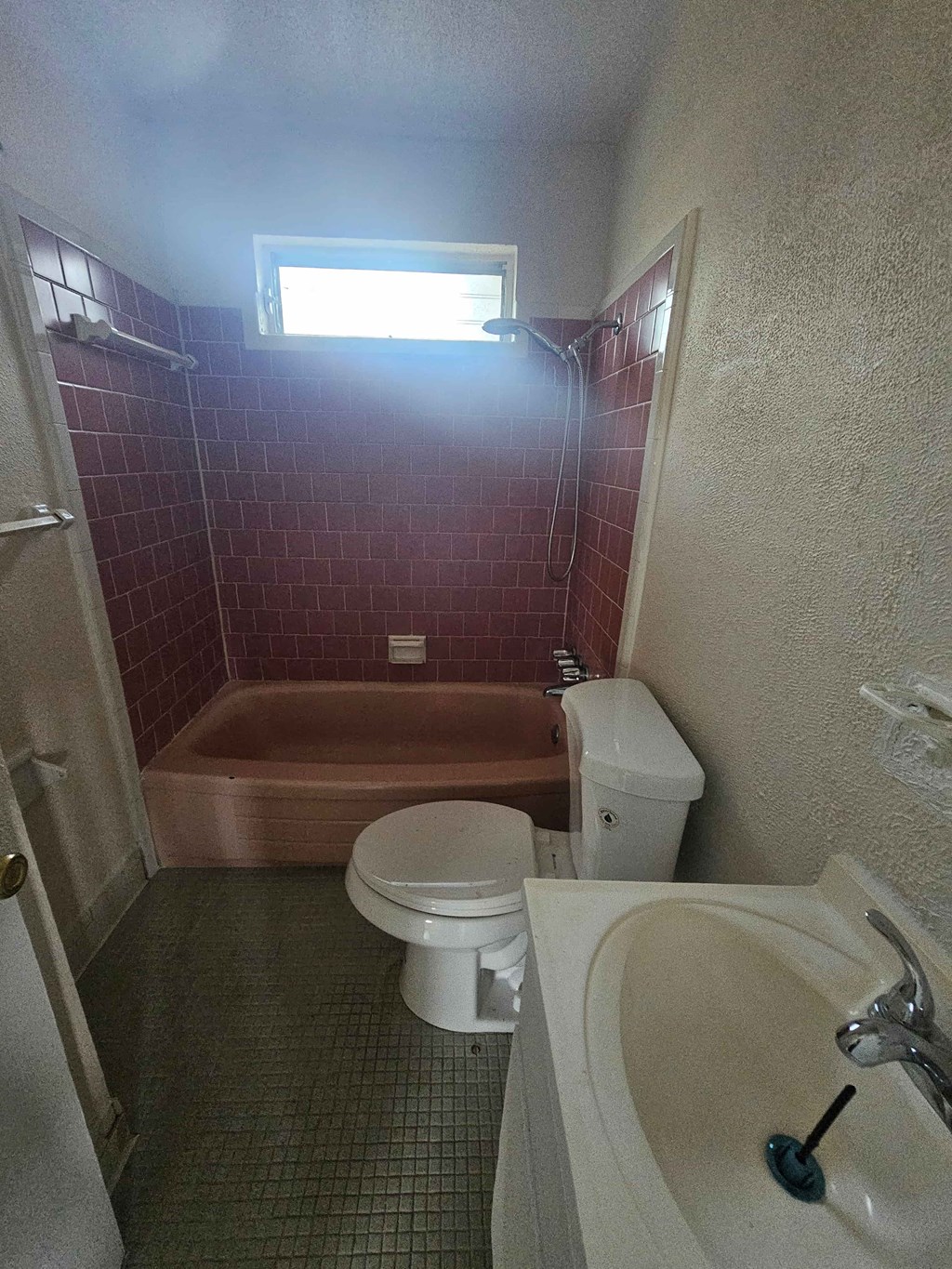 A small bathroom with a toilet, sink and bathtub.