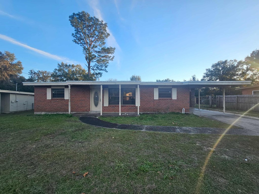 A small building with a red brick exterior and a white door is surrounded by a grassy area.