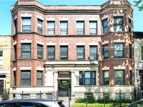 A large red brick building with a black iron fence in front.