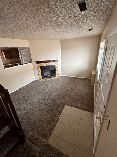 A living room with a fireplace and a staircase.