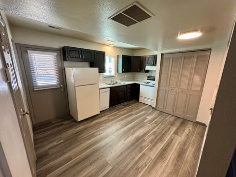 A kitchen with a white refrigerator and wooden floors.