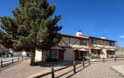 A house with a brown roof and a tree in front of it.