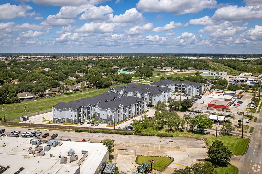 A large white building with a grey roof is surrounded by a parking lot.